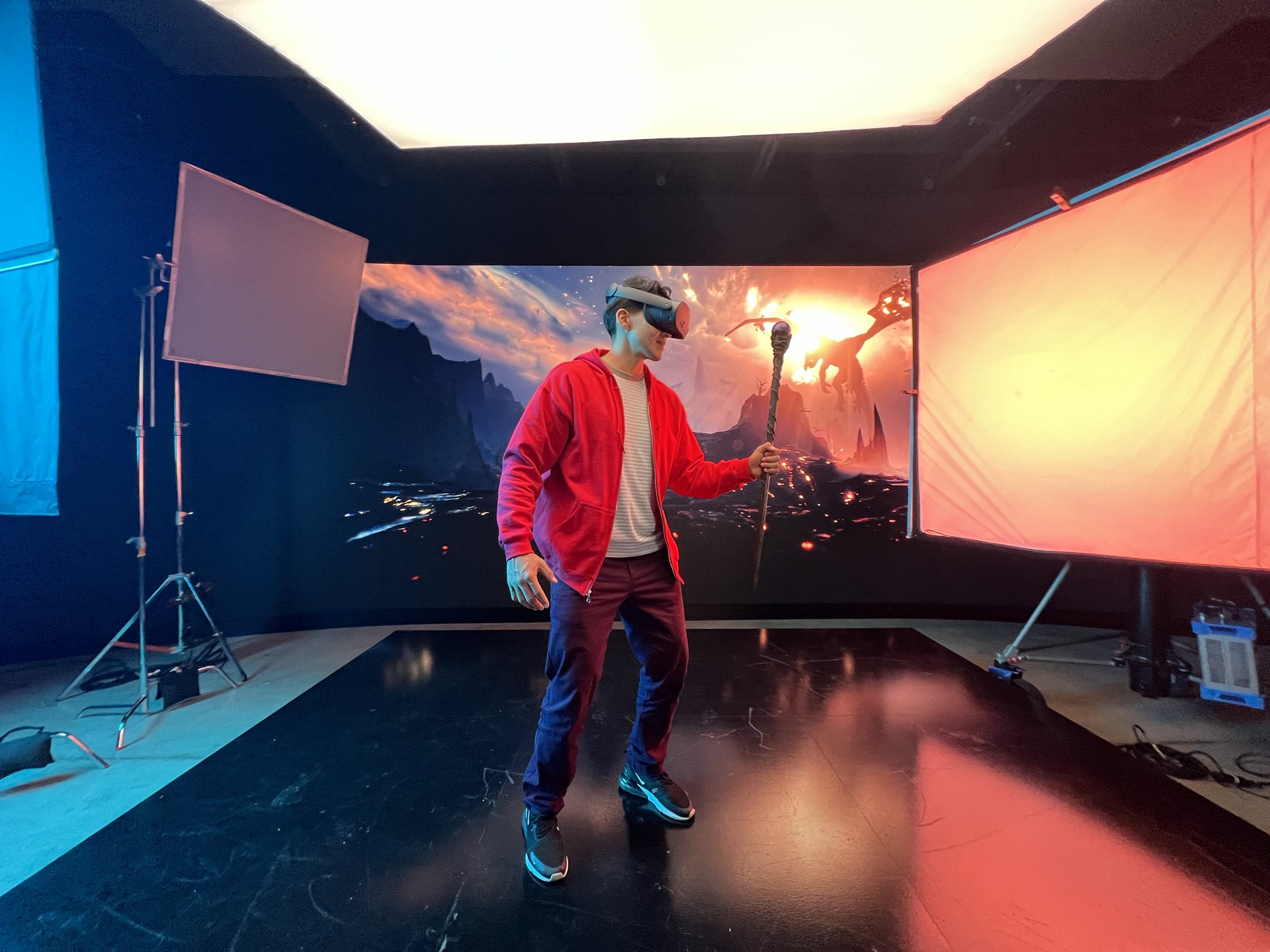 Talent wearing mixed reality headset and red jacket performing on LED volume stage displaying dramatic volcanic landscape with fiery skies at Vossler Studios for Qualcomm XR product shoot