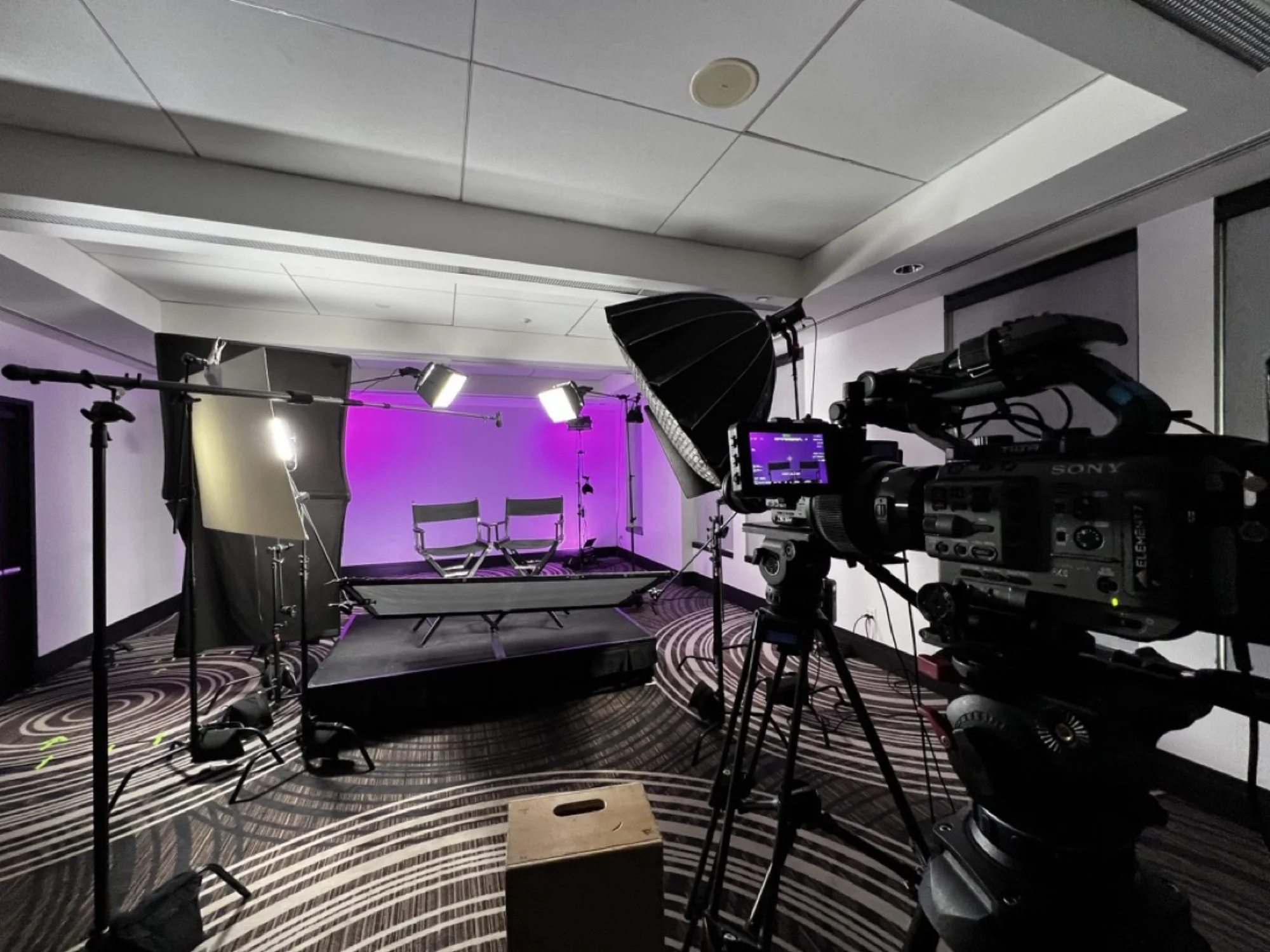 Full lighting package with softboxes, LED panels, C-stands, and purple cyclorama backdrop — Sony camera with Element 7 branding