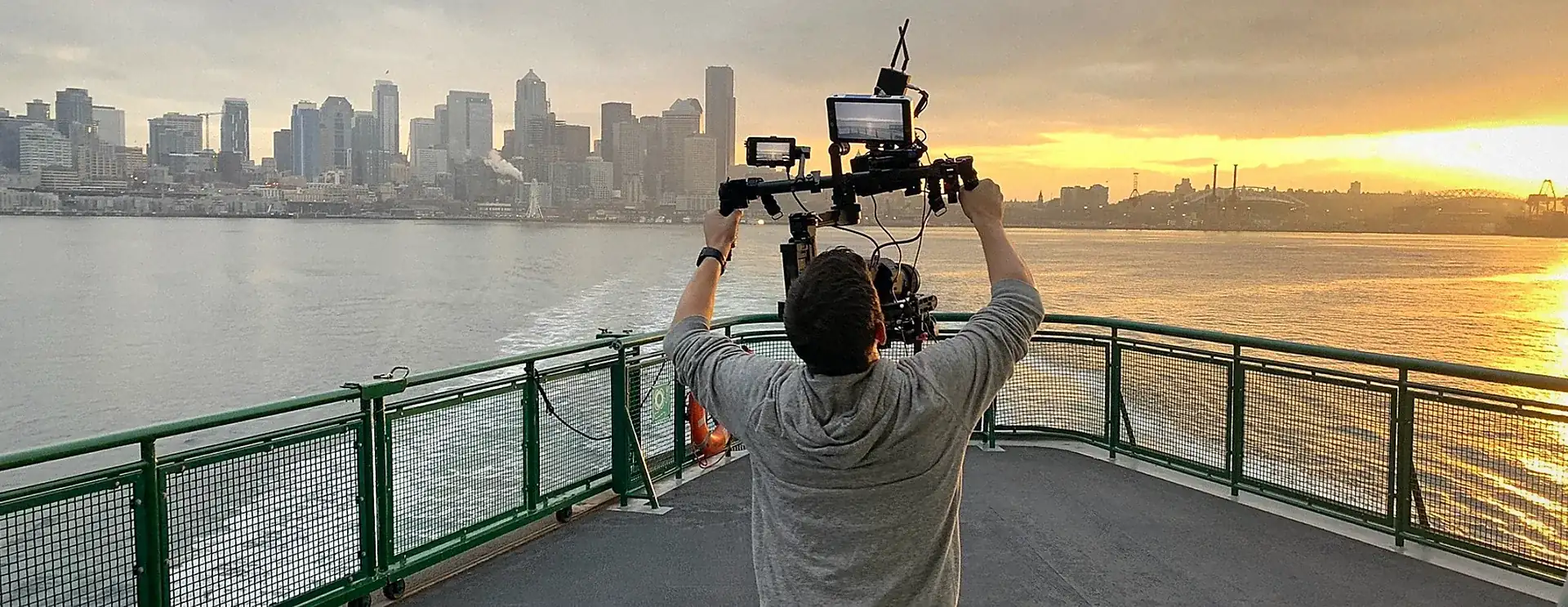 Element 7 filmmaker raising a camera rig toward the Seattle skyline at sunset