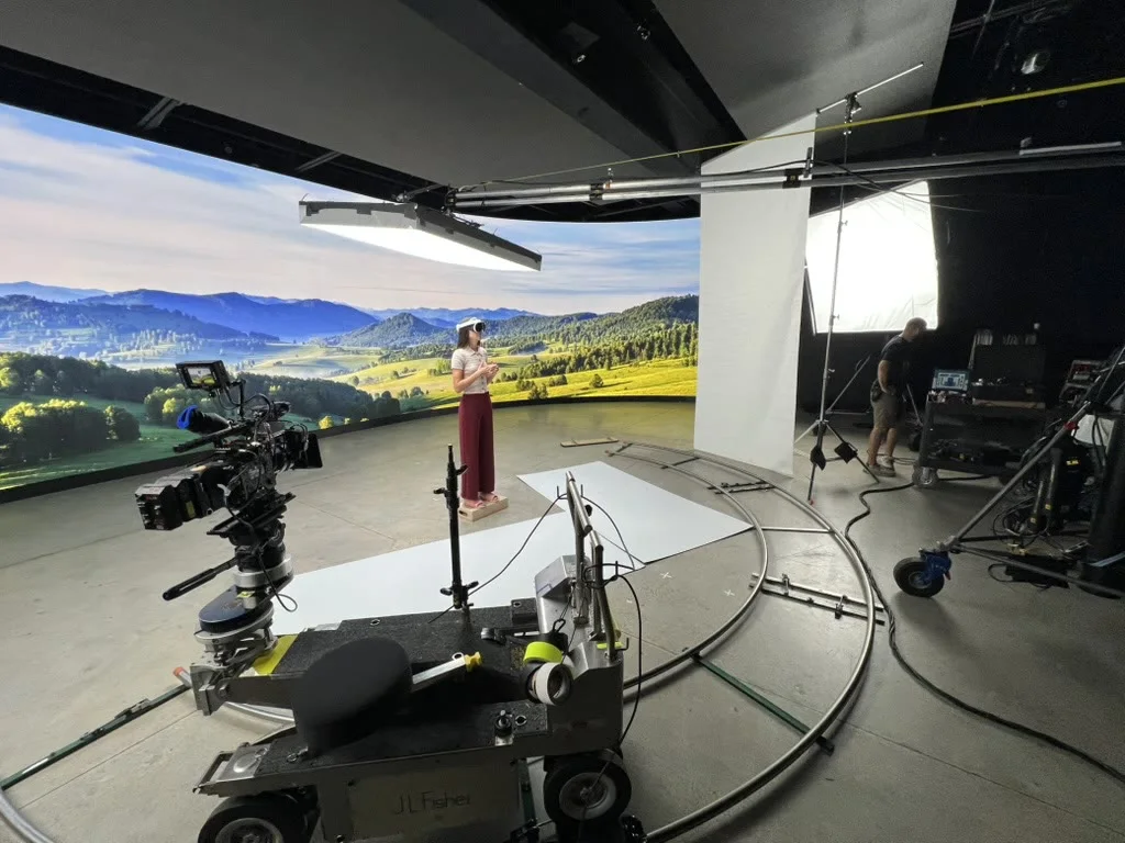 Behind-the-scenes LED volume production set with camera dolly, crew, talent, and scenic wall backdrop